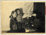 Sisters Halina  and Eva Litman pose next to a basket of flowers while in hiding in Jaroslaw.