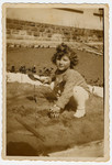 Halina Litman digs in a garden, wearing a sweater knitted by her mother with the initial 'H'.