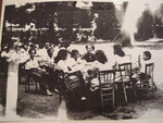 Teenagers from the Versailles children's home sit outside around tables.