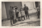 A group of civilians poses next to members of the German army.