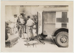 Concentration camp survivors stand next to an ambulance.