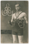 Studio portrait of Yehuda Bielski performing calisthenics with weights.