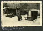 A Polish Jew wrapped in a blanket stands in the snow outside a basement apartmnet.