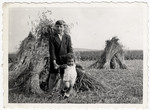 Abraham Malach poses with his baby cousin Abraham Reichman in front of a haystack near the Amberg displaced persons' camp.