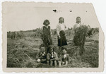 Three young Jewish children pose outside in a field in the Belgian countryside, where they are being hidden on the farm of a German maid.