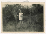 A young Jewish girl who is living in hiding poses outside in a field.