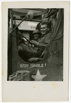 Two young American soldiers smile in their army vehicle.