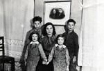 Marta Raifeld Welner poses with her four children in her home underneath a photograph of her inlaws.