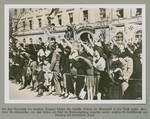 A crowd, mostly women and children gives the Nazi salute.