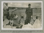 A man in German military uniform stands before a group of Arab men and women.