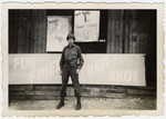 An American soldier stands in front of a Buchenwald barracks plastered with anti-Nazi signs.