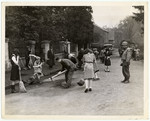 An American soldier supervises German civilians forced to clean the streets of Herzogenrath, Germany, in compliance with orders issued by the Military Government of the town.