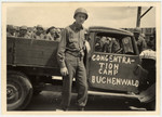 An American soldier stands in front of a truck labeled "Concentration Camp Buchenwald."