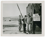 American military personnel and a liberated prisoner stand by a quarantine sign near the entrance of the Dachau concentration camp.