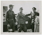 Herman Goering and his adjutant stand next to an airplane accompanied by an American soldier shortly after his capture.