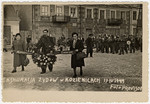 Survivors carrying a wreath and banner march in a funeral procession during the exhumation and reburial ceremony in Kozienice of Nazi victims.