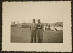 Jesse Owens, American track-and-field Olympic athlete, wearing his Ohio State University track suit, poses with another gentleman.
