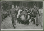 Major Shipway and Lt. Marcel Frank carry a large floral wreath to the mass grave of 243 slave laborers who were shot by their guards on the railway lines at Lueneburg on the way to the Belsen Camp.