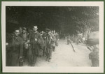 A column of former French prisoners marches down a road in Germany on their return to France.