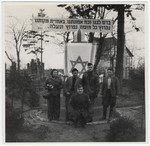 Five people, including members of the Frankfurt Jewish GI Council pose in front of a memorial in a German displaced persons' camp.