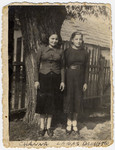 Two young women stand outside by a fence in Zhetel, Poland.