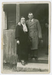 Nechama Schmidt and Efraim Tykocka  pose by the entrance to a wooden building.