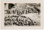 American soldiers walk among corpses that are laid out in rows in the Nordhausen concentration camp.
