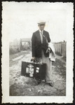 Portrait of a man [possibly Philip Roiter] carrying a suitcase down an unpaved road in an unidentified locale.
