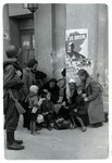 A Polish family huddles around a column in front of the Opera House in besieged Warsaw while a Polish soldier looks on.