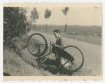 Louis Baars repairs his bicycle by the side of a road.