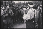 Philip Drell takes photograhs of the surrender of Dachau camp guards while liberated prisoners look on.