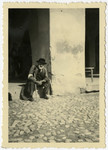 A Jewish man sits on a door stoop in the Krosno ghetto.