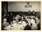 Young religious Jewish boys sit around a table at the Yeshiva of Eragny, headed by a group of rabbis, including Rabbi Zalman Schneerson.