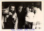 A mohel pours a glass of wine in advance of performing a brit milah (ritual circumcision) in the Feldafing displaced persons' camp.