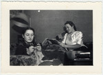 Rosa and Gret Luly read and knit in the Herzog's parlor.