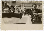 Two Bulgarian Jewish families sit around a table and share a meal.