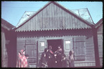 A group of women and children enter a wooden building marked with a Jewish star.