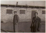Two survivors of the Hanover-Ahlem concentration camp stand in front of a barrack.