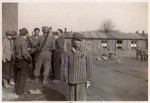 A young survivor of the Hanover-Ahlem concentration camp poses in front of a group speaking to an American soldier.
