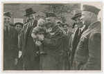 General Lucius Clay holds Gitla Fridling in his arms during a tour of the Schlachtensee displaced persons camp.