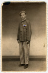 A young survivor of Buchenwald poses in his camp uniform several months after liberation; his camp number has been drawn onto the photo.
