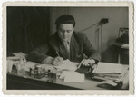Izack [last name unidentified] works at a desk in the Salzburg displaced persons camp.