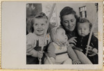 Dora Kohl poses with her two children Miriam and Sam and an unidentified baby in the Hofgeismar displaced persons camp.