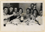 A group of friends gather around a table for a celebration in the Hofgeismar displaced persons camp.