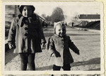 Two young children stand on a street of the Hofgeismar displaced persons camp.