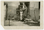 Oscar Kalmar adjusts the bicycle of a friend in prewar Zlate Moravce.