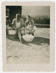 Three young women peel potatoes into large bowls in the Holzhausen displaced persons camp.