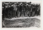 Newly liberated prisoners stand around a mass grave at Dachau concentration camp.