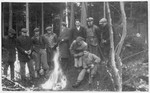 Workers from the Lipa labor camp gather by a fire in the woods.