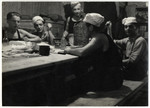 Workers sit  by a table in the kitchen of the Lipa farm labor camp.